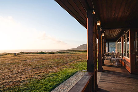 a porch with a view of a field and mountains