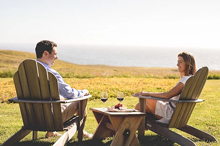a man and woman sitting in chairs with drinks and a table