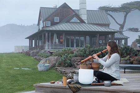 a woman sitting on a porch playing a flute