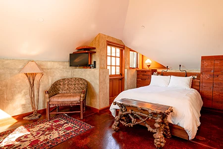 a bedroom with a bed, a large chair and a door to outside