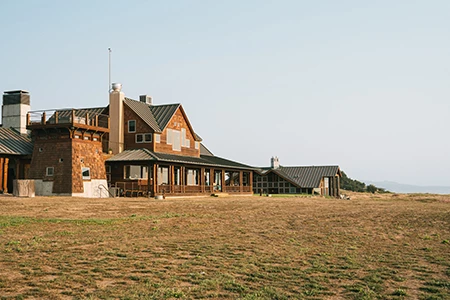 a large brown building with a large grassy field