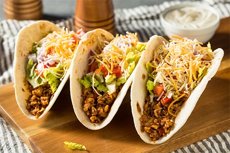 a group of tacos on a wooden board