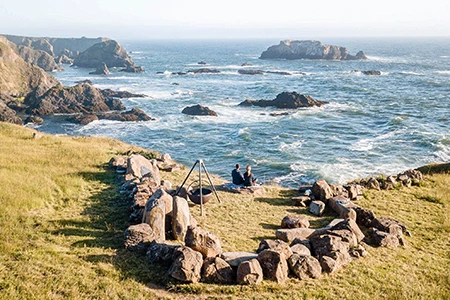 a couple sitting on grass by the ocean