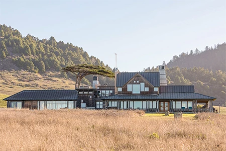 a large house with a grassy field and trees in the background