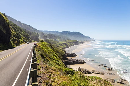 a road with a body of water and trees