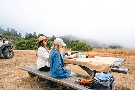 two women sitting at a picnic table