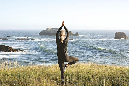 a woman standing on one leg with hands up in the air