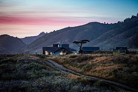 a house in a field with mountains in the background