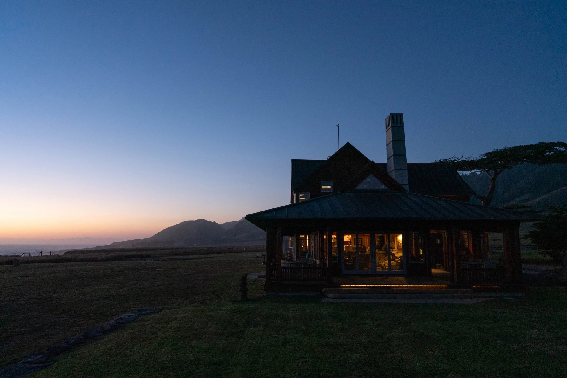 a house with a large lawn and mountains in the background