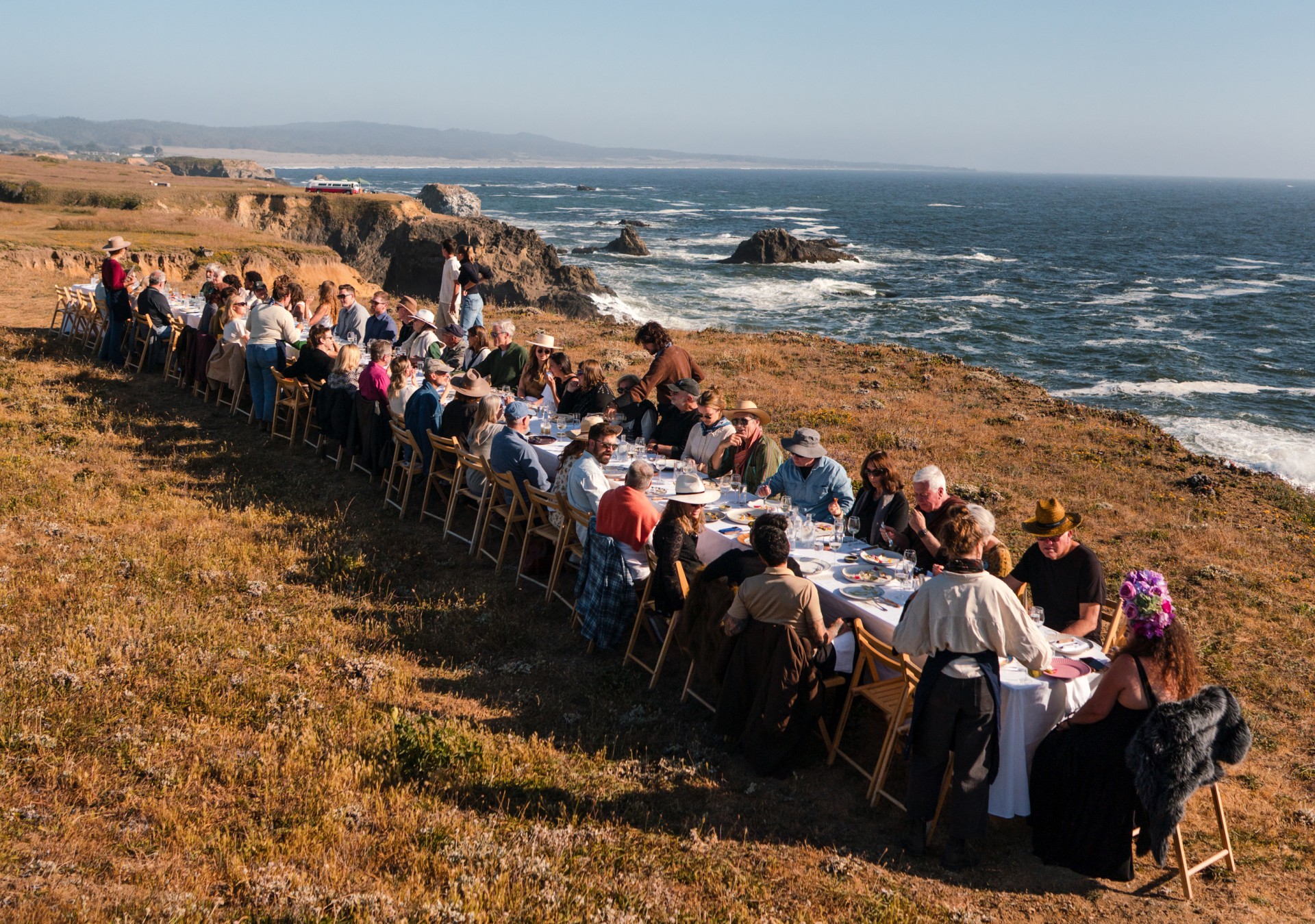 a group of people sitting at a long table with a long table with food on it