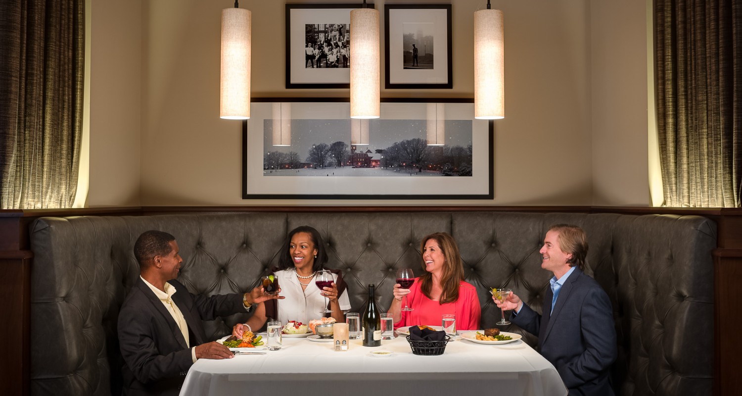 a group of people sitting at a table with food and drinks