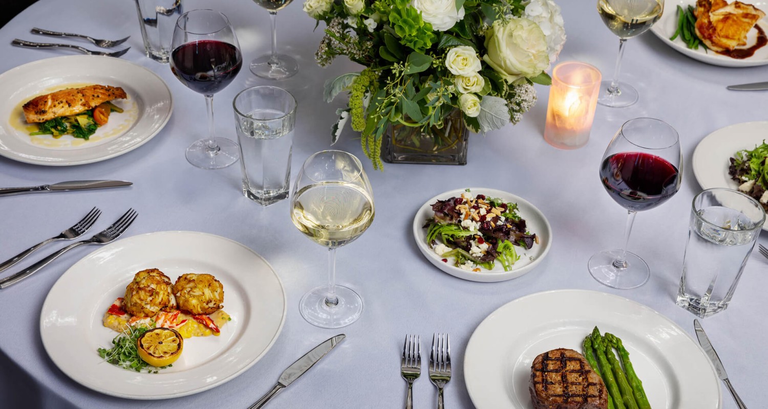 a table with plates of food and wine glasses