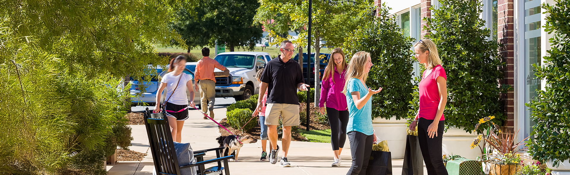 a group of people walking a dog on a sidewalk