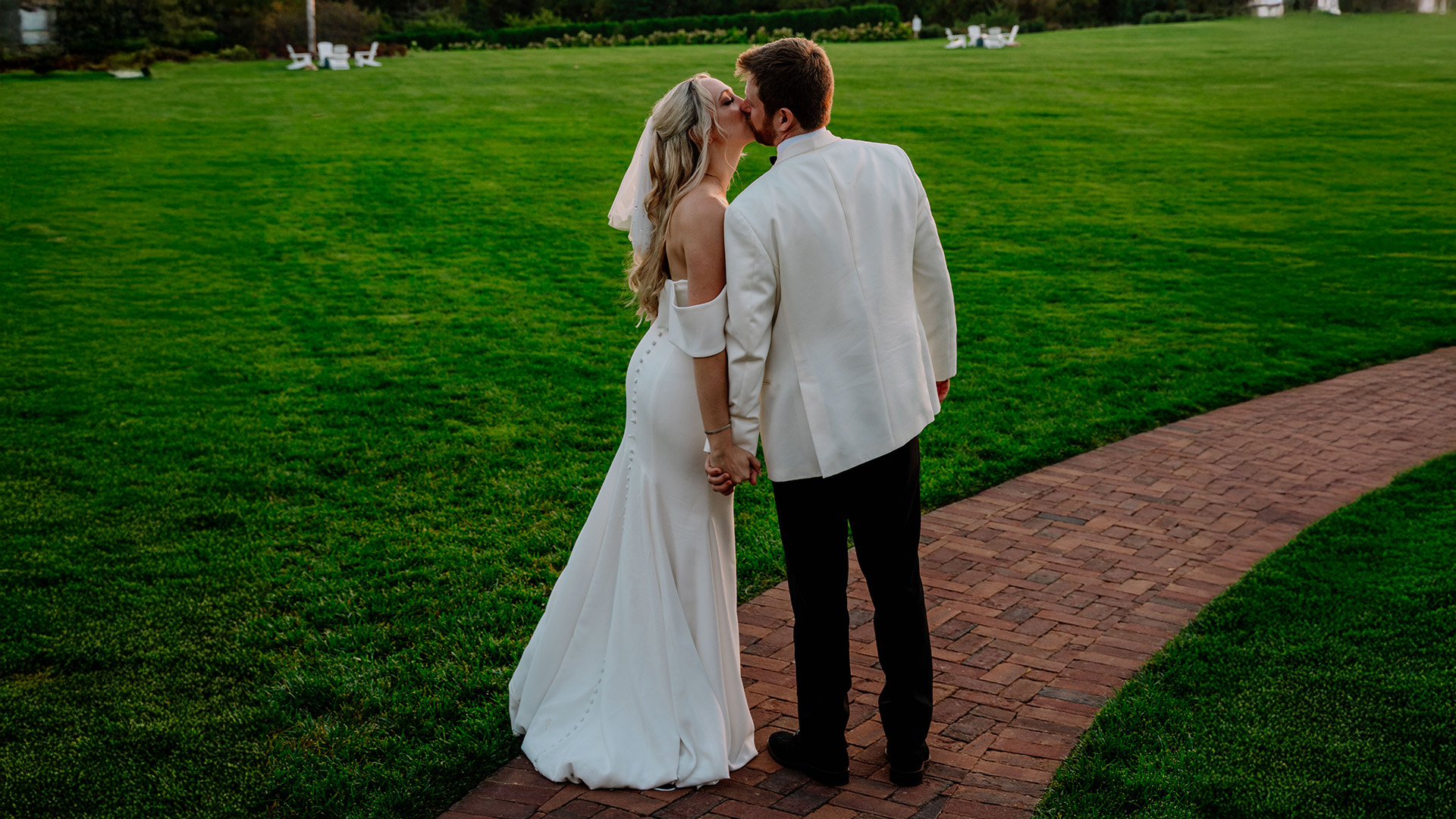 a man and woman kissing on a brick path