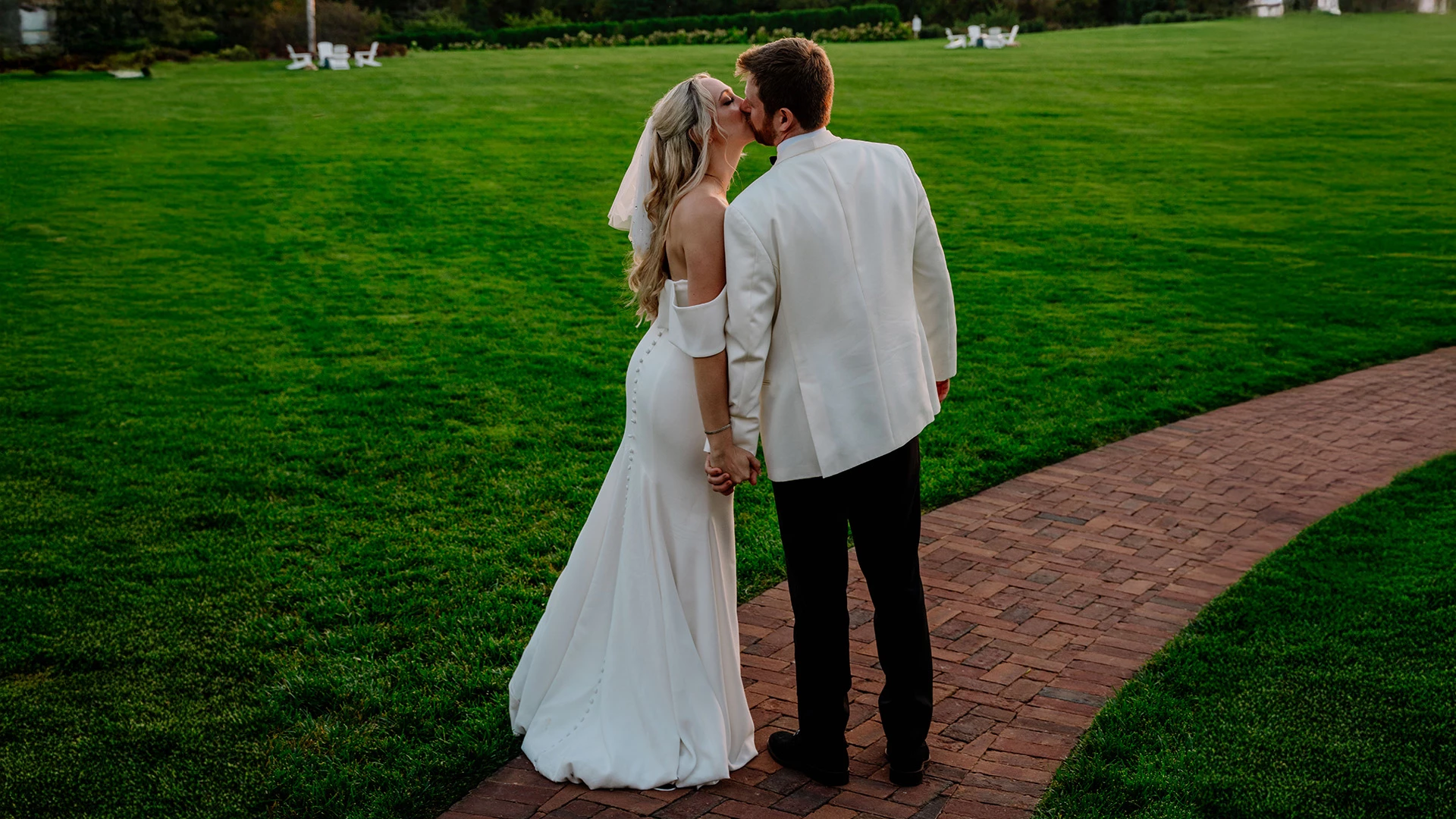 a man and woman kissing on a brick path