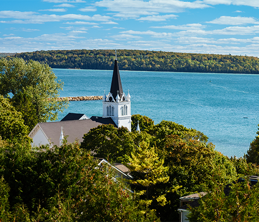 a white building with a steeple by a body of water