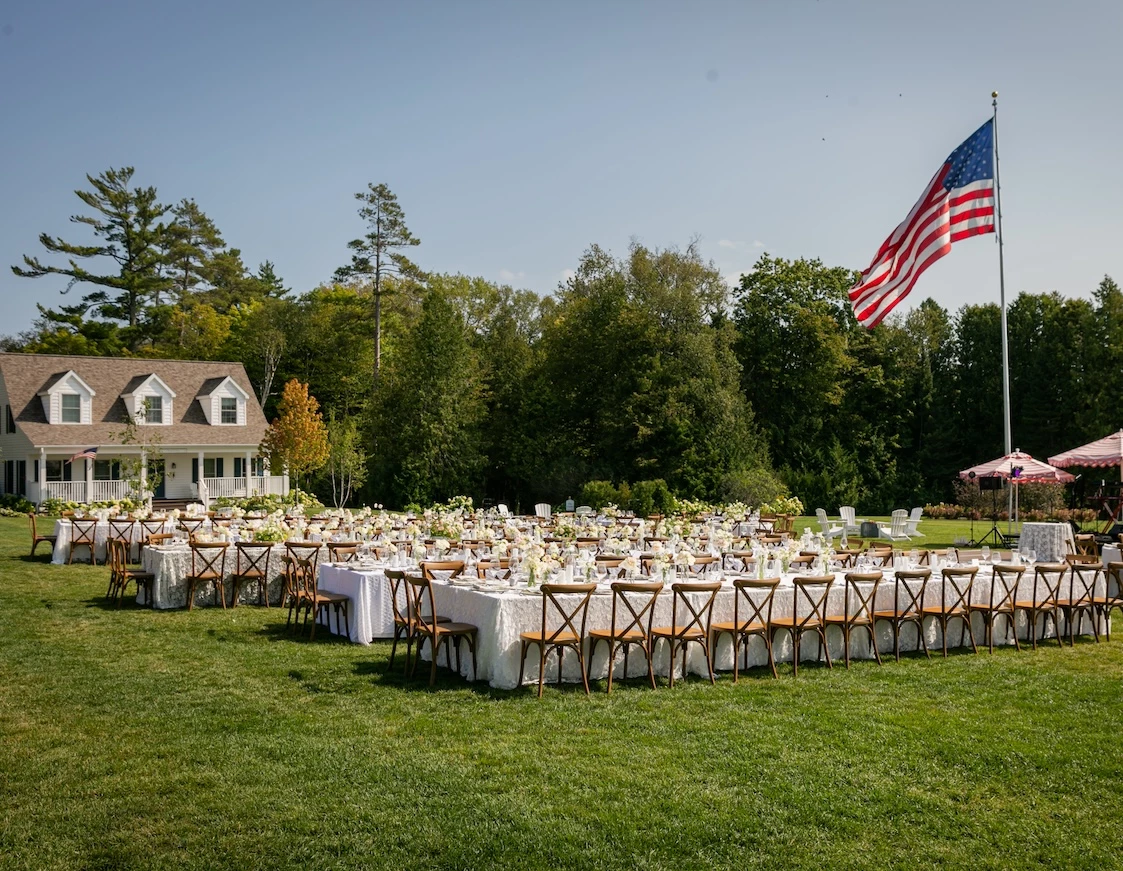 a large group of tables and chairs in a lawn with a flag