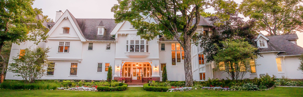 a large white house with a tree and lawn