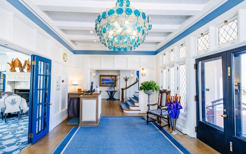 a blue and white hallway with a chandelier and blue carpet