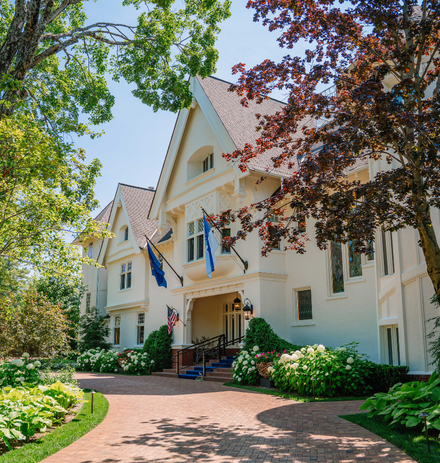a large white house with trees and flags