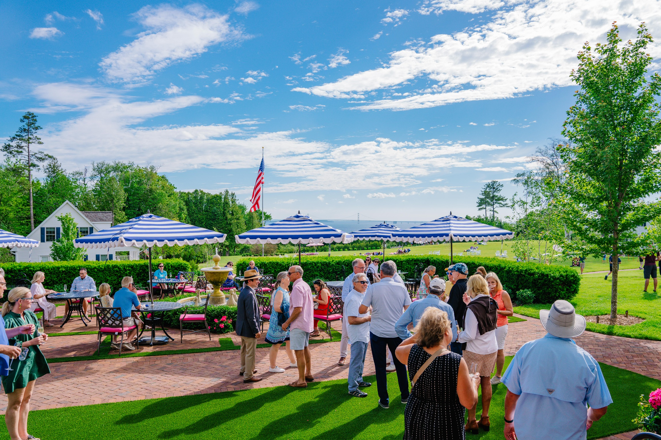 a group of people standing on a brick path with tables and umbrellas