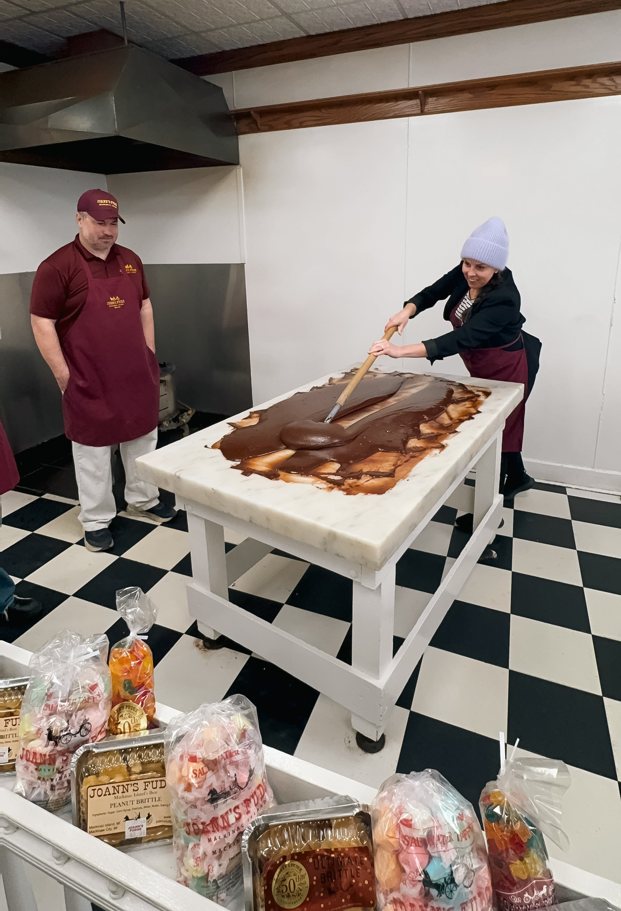 a woman in a hat and apron mixing chocolate on a large table