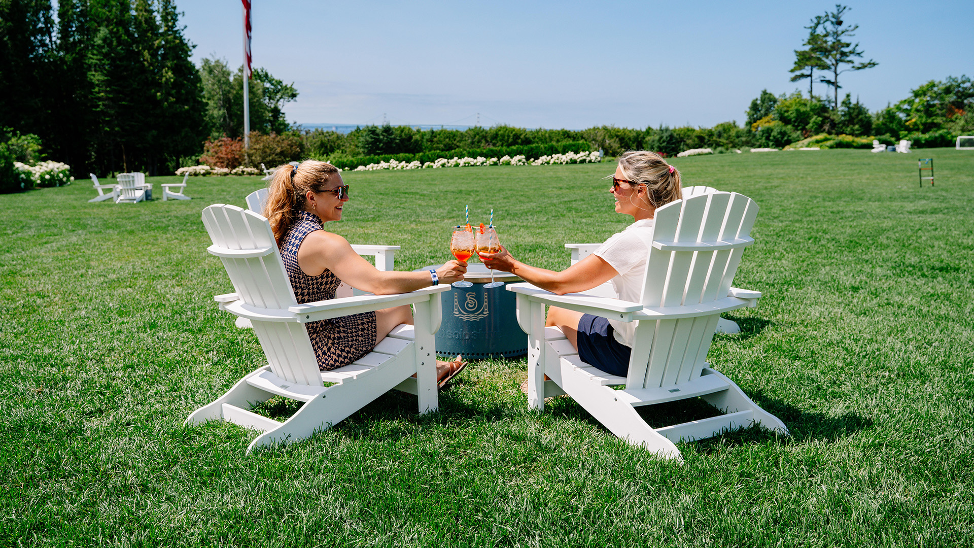 two women sitting in lawn chairs holding drinks