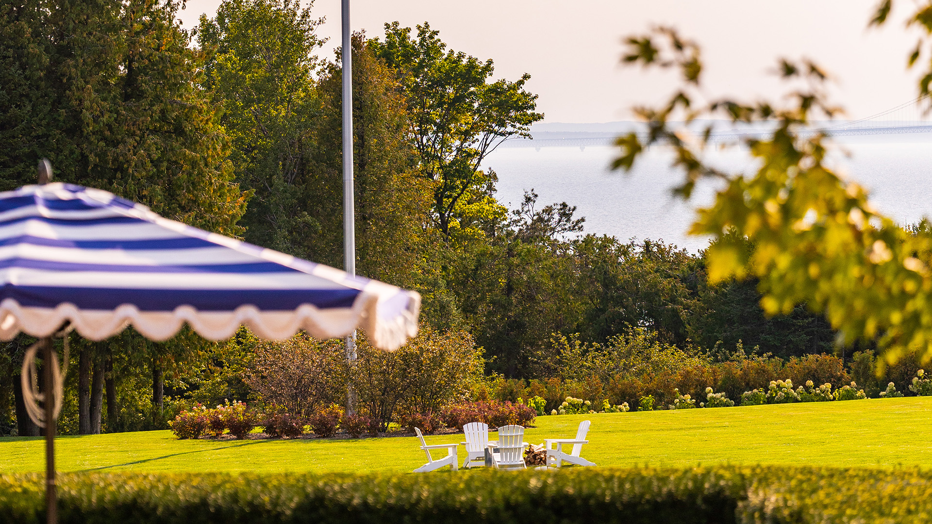 a lawn with chairs and a striped umbrella