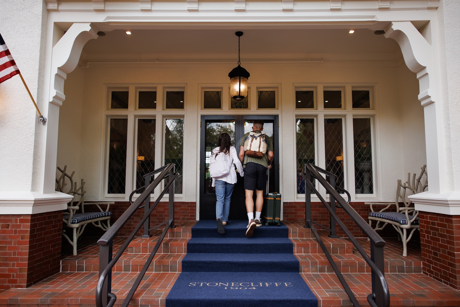 Guests walking up the front entrance stairs of The Inn at Stonecliffe, a historic luxury Mackinac Island hotel with classic architecture and inviting atmosphere