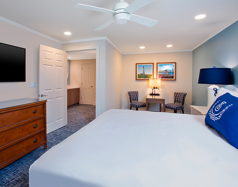 a room with a bed, two chairs, and a television