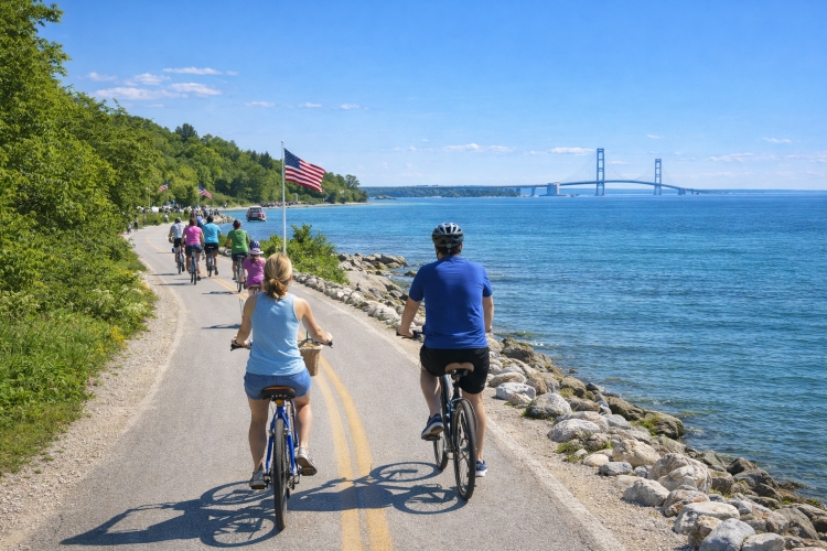 Cyclists riding the Mackinac Island M-185 bike loop along Lake Huron during Memorial Day weekend