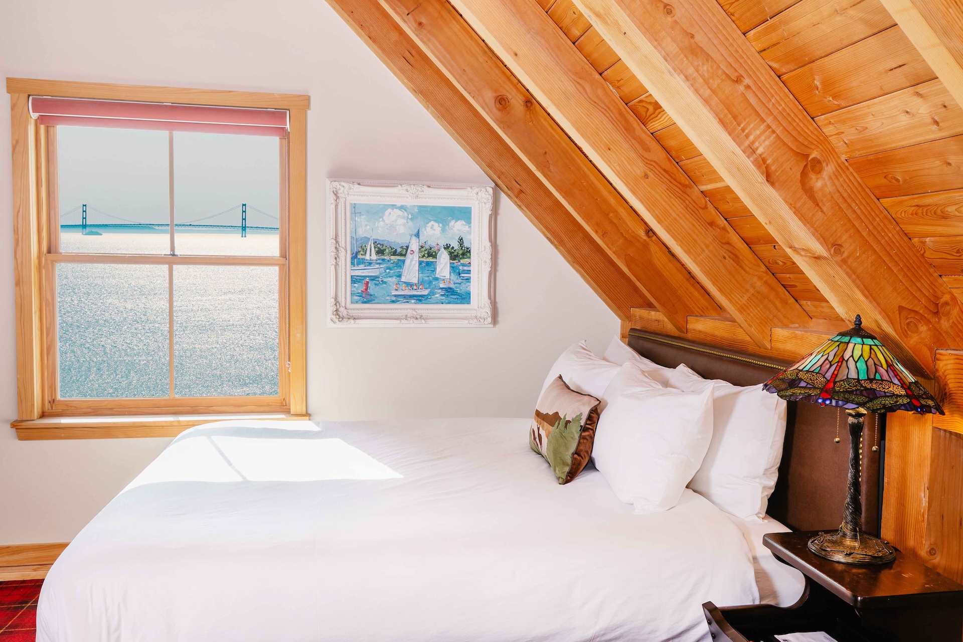 a bed in a room with a wooden ceiling and a window