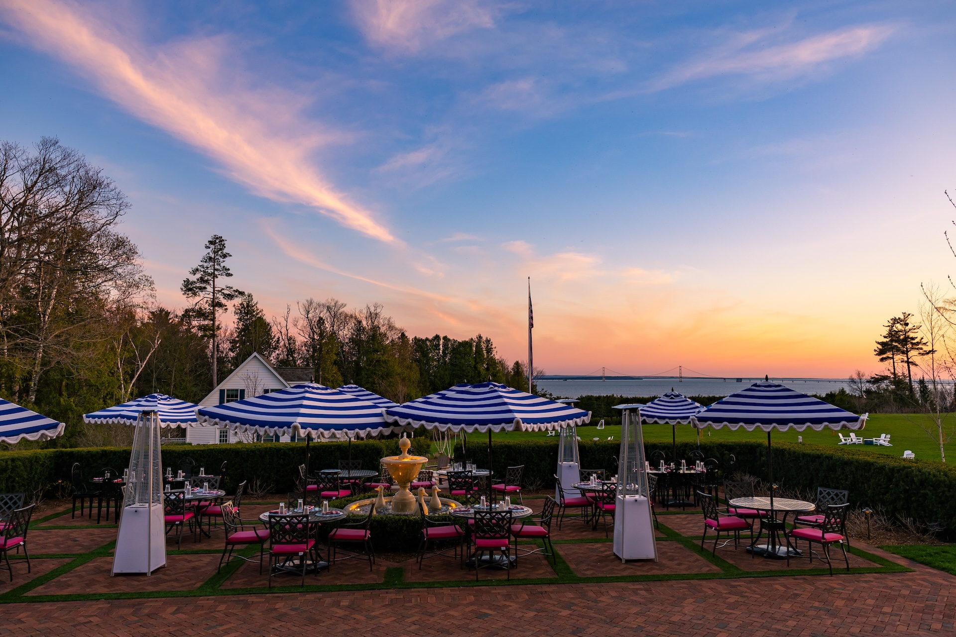 a group of tables and chairs with umbrellas in a yard