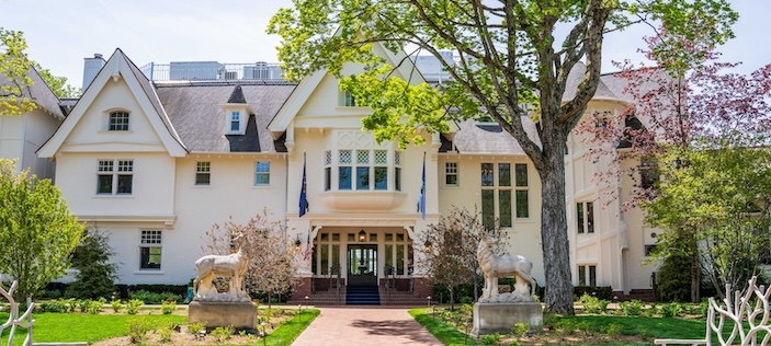 a white house with a stone walkway and statues of animals