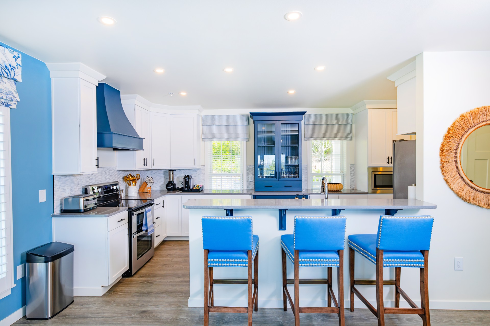 Yacht Watch Cottage full kitchen with blue cabinetry, island seating, and stainless steel appliances at The Inn at Stonecliffe on Mackinac Island