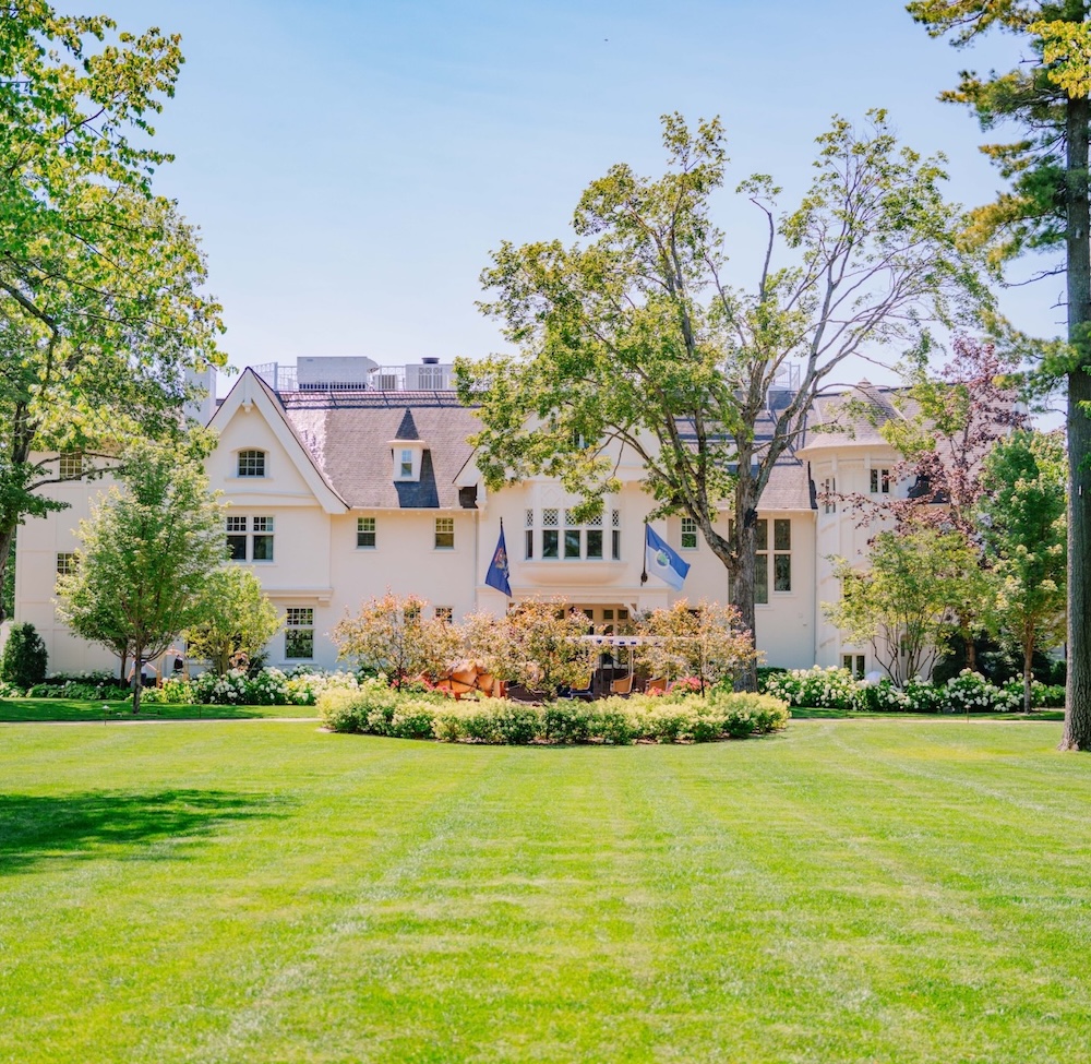 a large white house with a lawn and trees