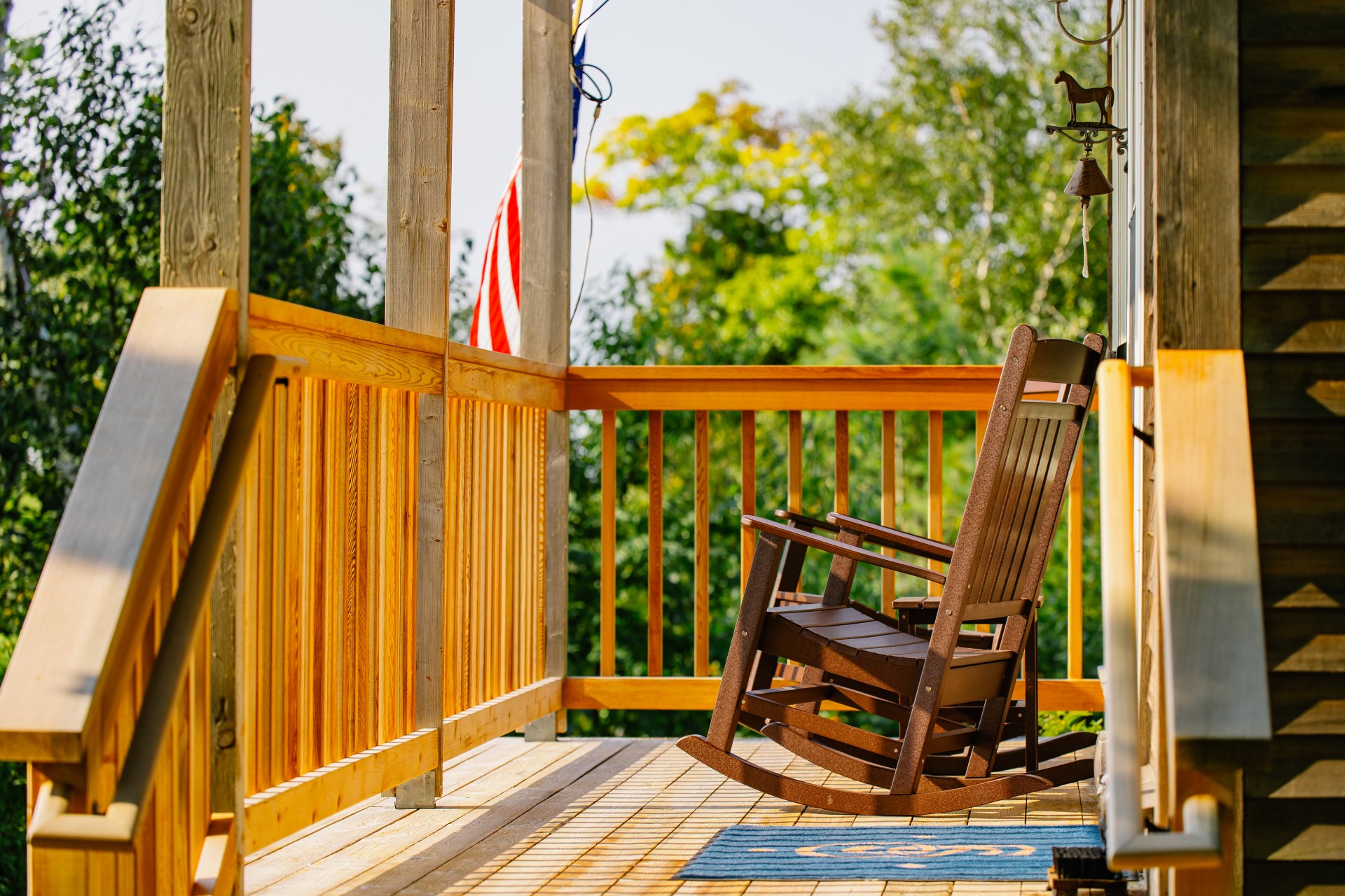 Love Shack cottage at The Inn at Stonecliffe on Mackinac Island with private porch, rocking chairs, and sunset views over Lake Huron and the Mackinac Bridge.