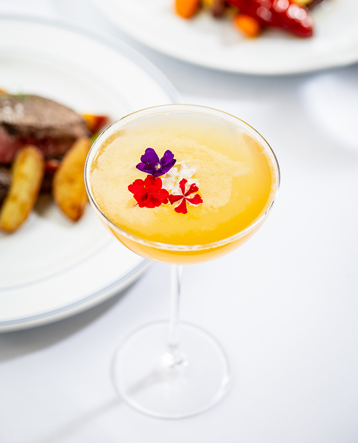 a glass with a drink and flowers on it
