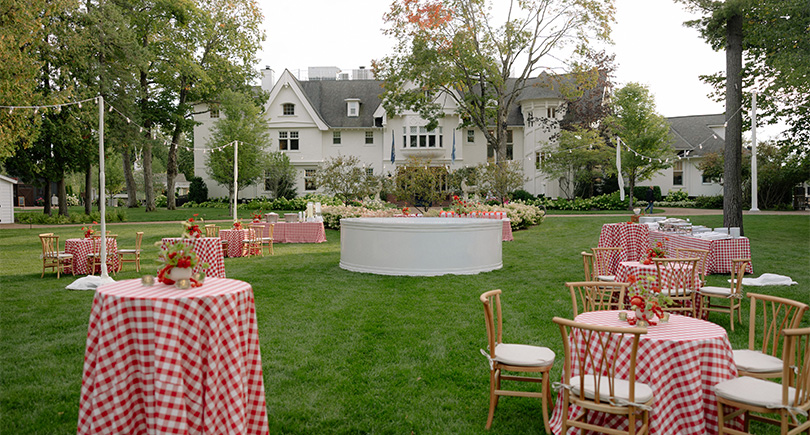 a lawn with tables and chairs and a white building