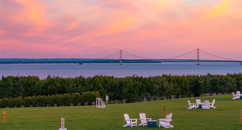 a lawn with chairs and a bridge in the background
