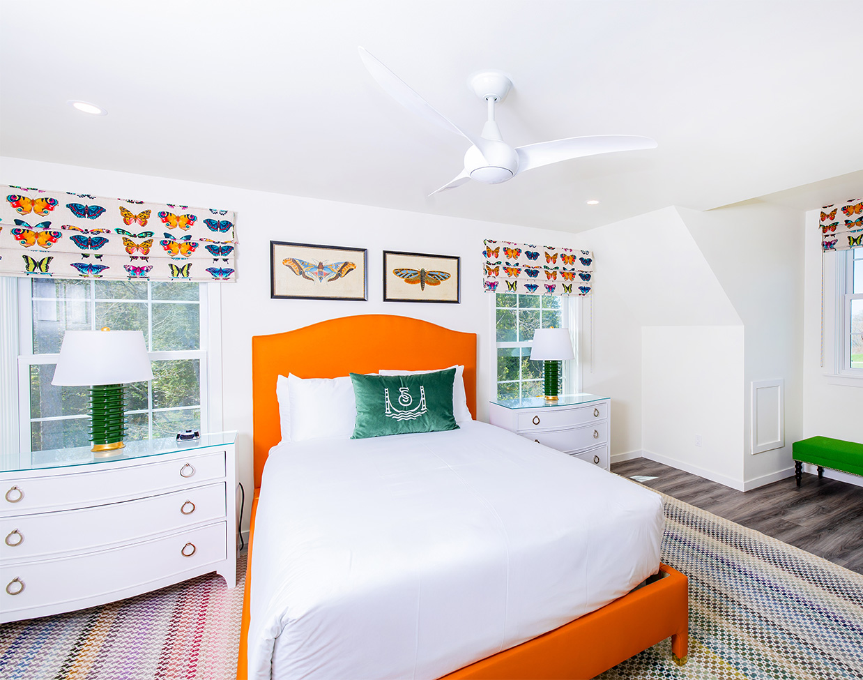 Bright guest bedroom with orange upholstered bed at The Inn at Stonecliffe, one of the distinctive Mackinac Island hotels.