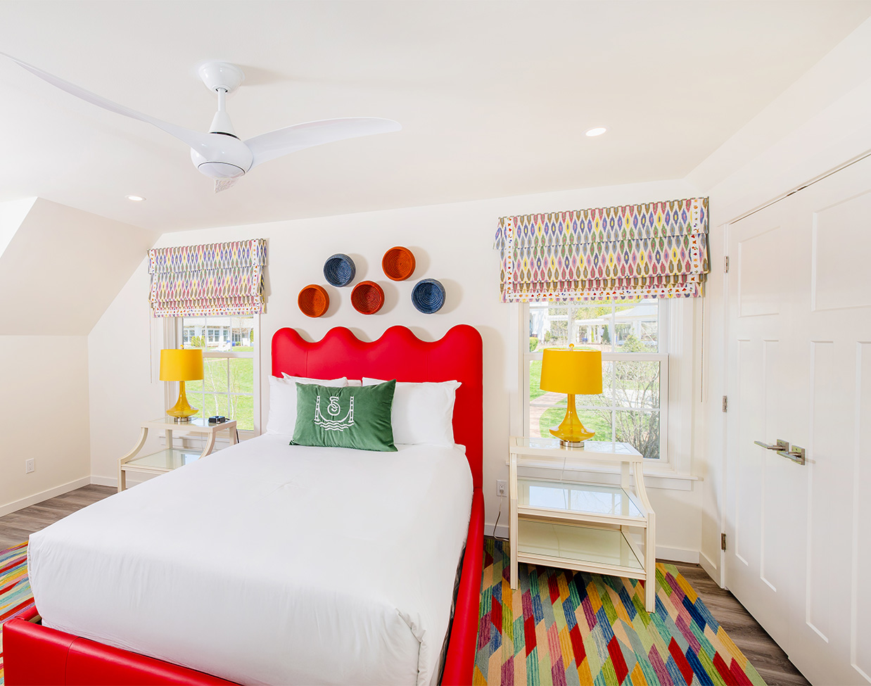 Guest bedroom with red scalloped headboard and colorful decor at The Inn at Stonecliffe, one of the distinctive Mackinac Island hotels.