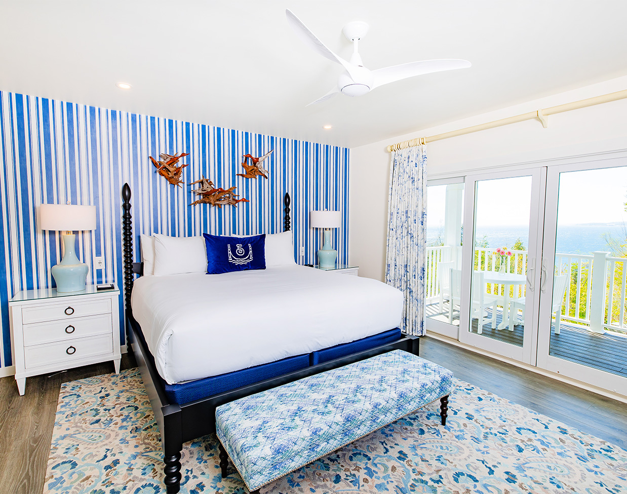 Blue-accented bedroom with balcony water views at The Inn at Stonecliffe, one of the scenic Mackinac Island hotels.