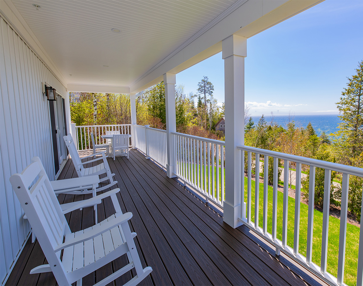 Covered porch with rocking chairs and water views at The Inn at Stonecliffe, one of the scenic Mackinac Island hotels.