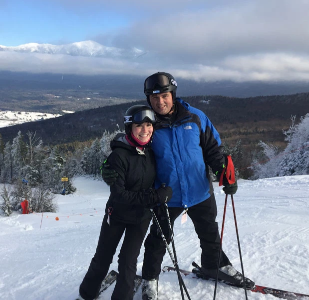 husband and wife at the top of the mountain while skiing