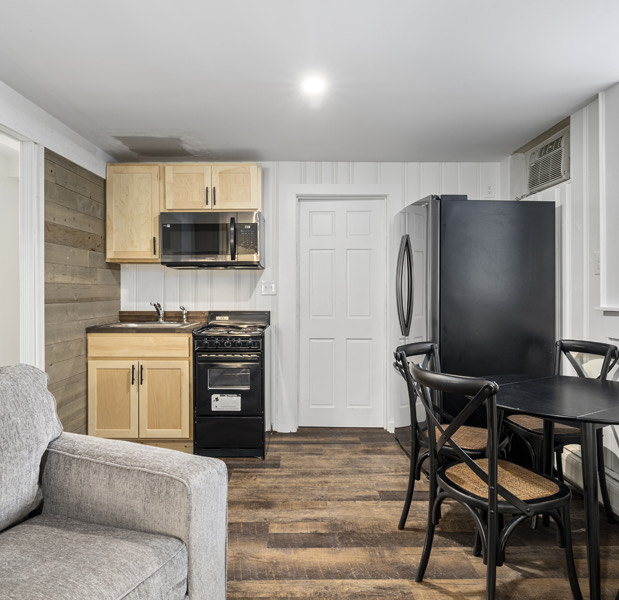 2 bedroom apartment with wooden floors, white walls, a small kitchen and a dining table