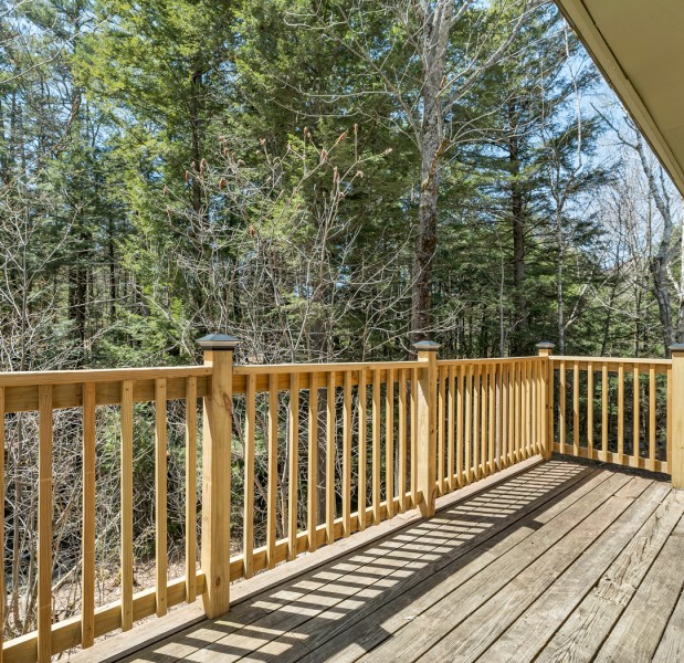 a deck with a railing and trees