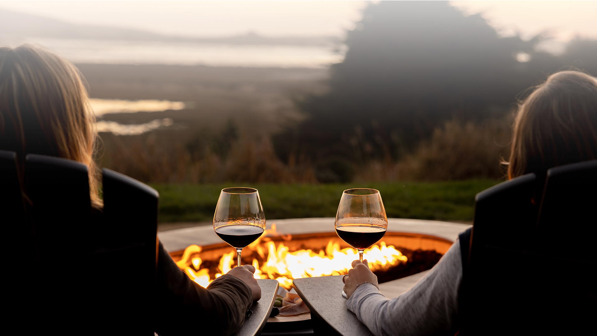two women enjoying a glass of wine fireside