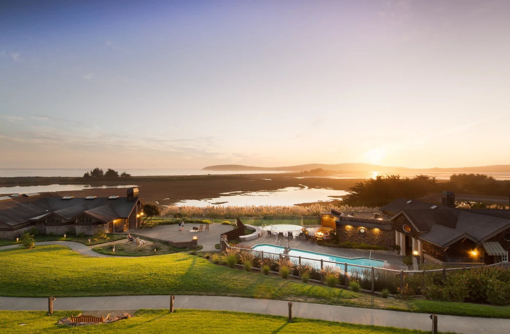 aerial view of the lodge at bodega bay with a blue pool and sunset in the back