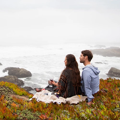 a couple sitting cliffside enjoying wine